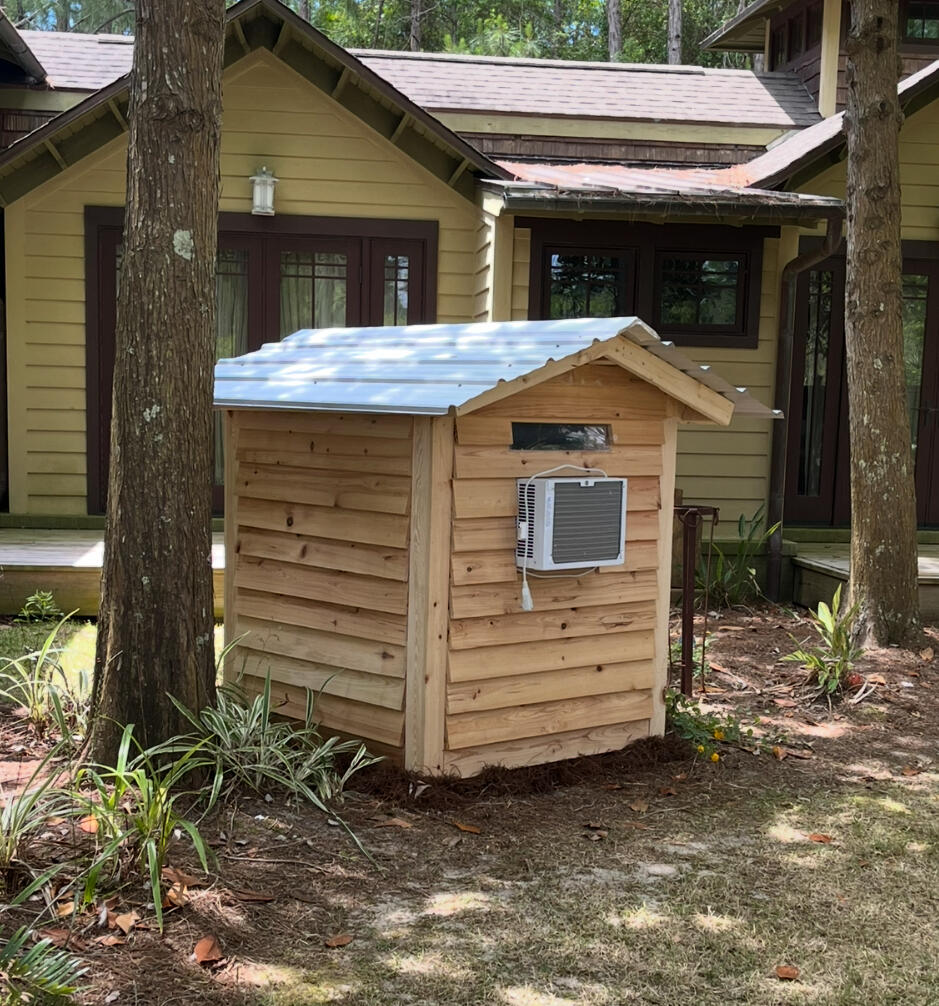 Custom cedar wrapped doghouse that is insulated, cooled, with a plexiglass window